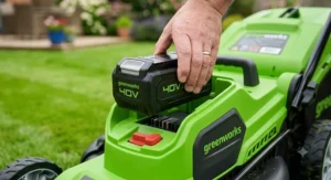 Close-up of a hand slotting the 40V lithium-ion battery into a Greenworks cordless lawn mower