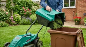 A close-up shot of lifting the grassbox off a Bosch electric lawn mower to empty grass clippings into a garden waste wheelie bin.