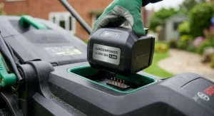 Close-up of a cordless electric lawn mower showing the lithium-ion battery pack being inserted.