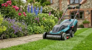 An electric lawn mower with a rear roller cutting right up to the edge of a garden flower bed.
