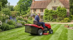 A rear discharge ride on lawn mower collecting grass clippings in a large country garden.
