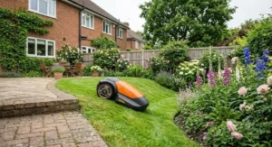 Robotic lawnmower traversing a sloping lawn alongside flower borders and patio edges.