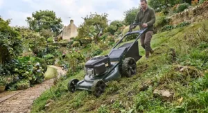 A durable self-propelled lawn mower navigating a steep garden gradient in the UK.