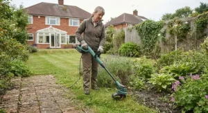Gardener using a lightweight cordless strimmer under £100 to tidy up garden borders in the UK.