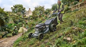 An operator using a reliable self-propelled lawn mower to safely cut grass on a steep embankment.